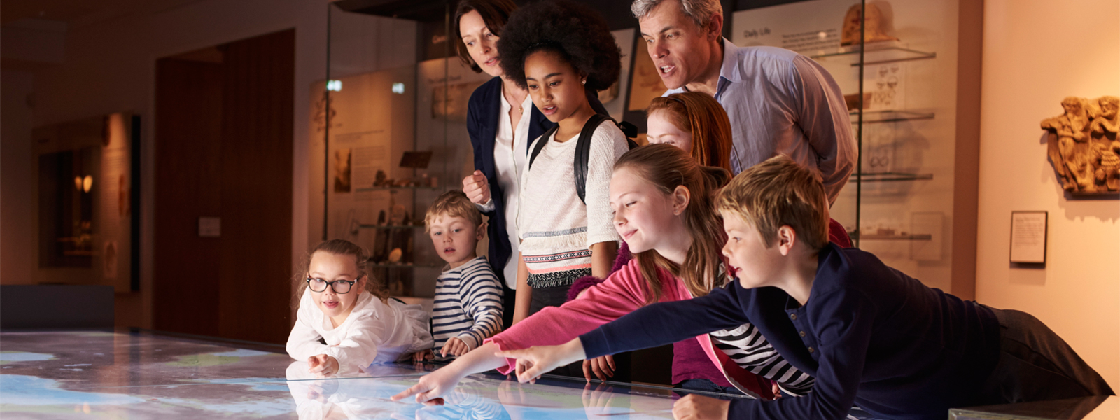 A group of teachers and students look over a map on a table.
